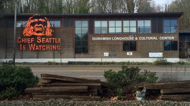 A sign reading “Chief Seattle is watching” with an image of Chief Seattle’s face, used in demonstration against an oil rig, on the side of Duwamish longhouse (Tran, 2020).